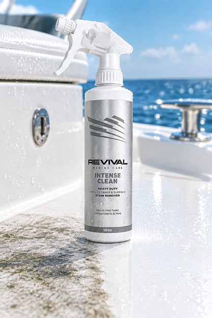 Una botella del quitamanchas de alta resistencia Revival Marine Intense Clean se encuentra sobre el casco blanco de un barco, con el océano azul y el cielo de fondo.